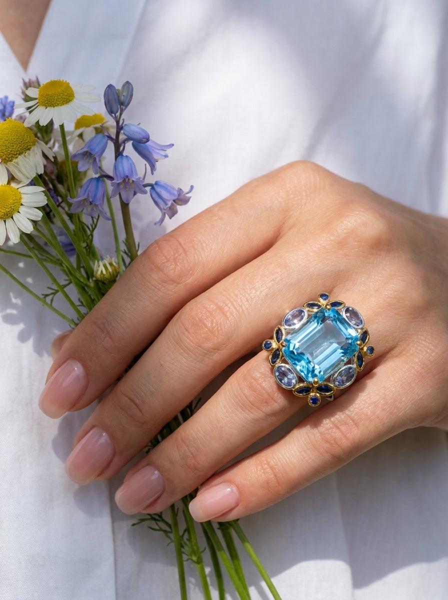 a woman in holding wild flowers flower and wearing large blue topaz ring