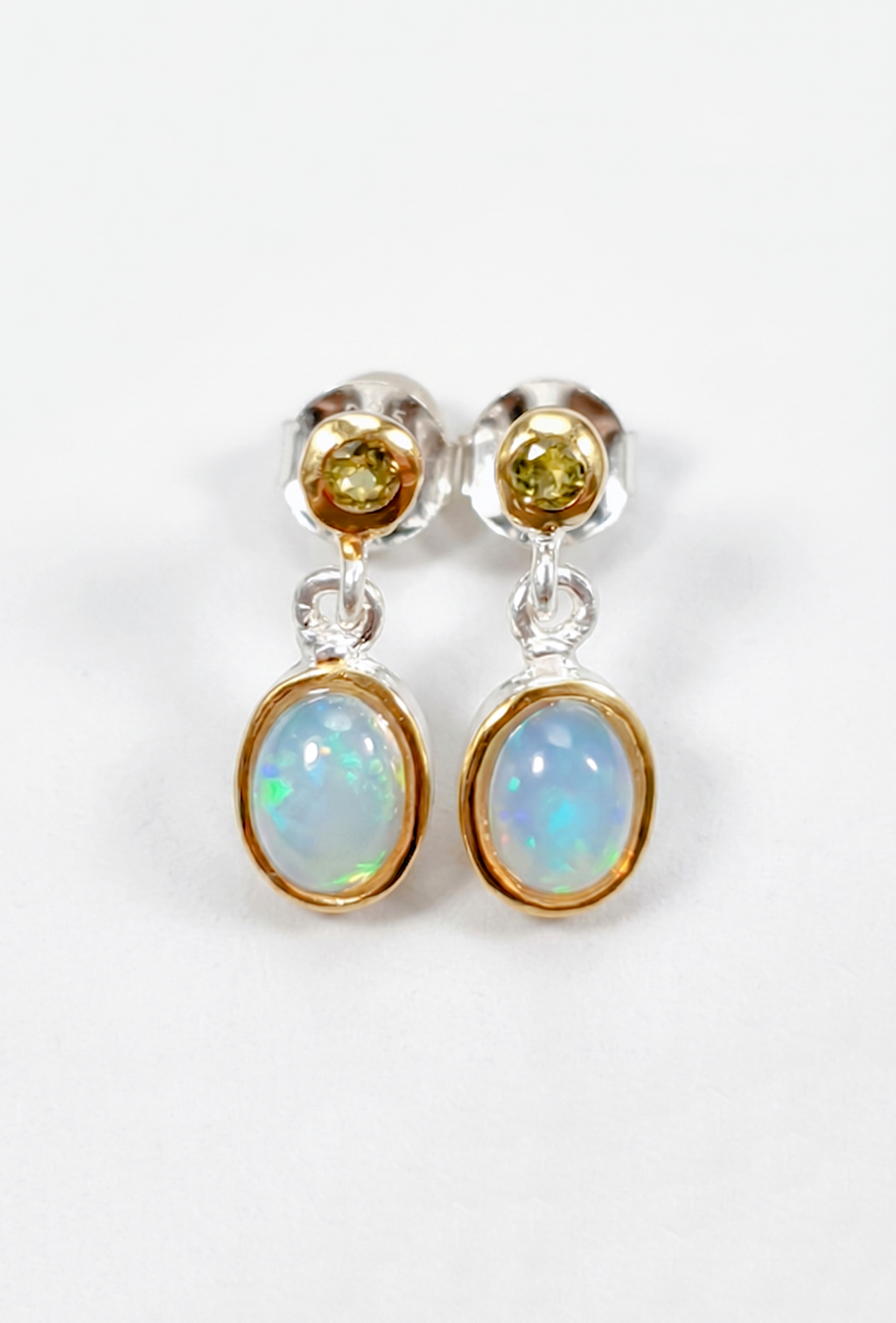 Pair of earrings with opal and yellow gemstones on a white background