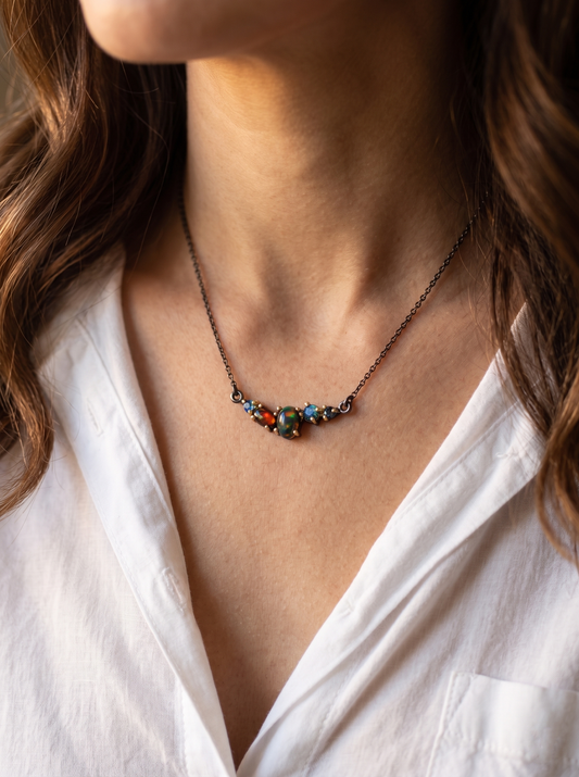 Necklace with black opal beads worn by a person in a white shirt.