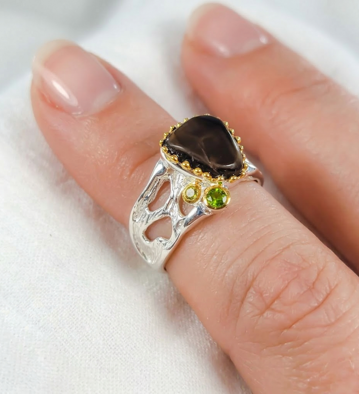 Silver ring with gemstones on a finger against a white background