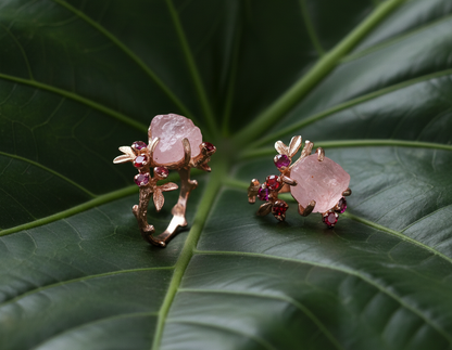 Pair of rings with pink stones and red gemstones on a green leaf