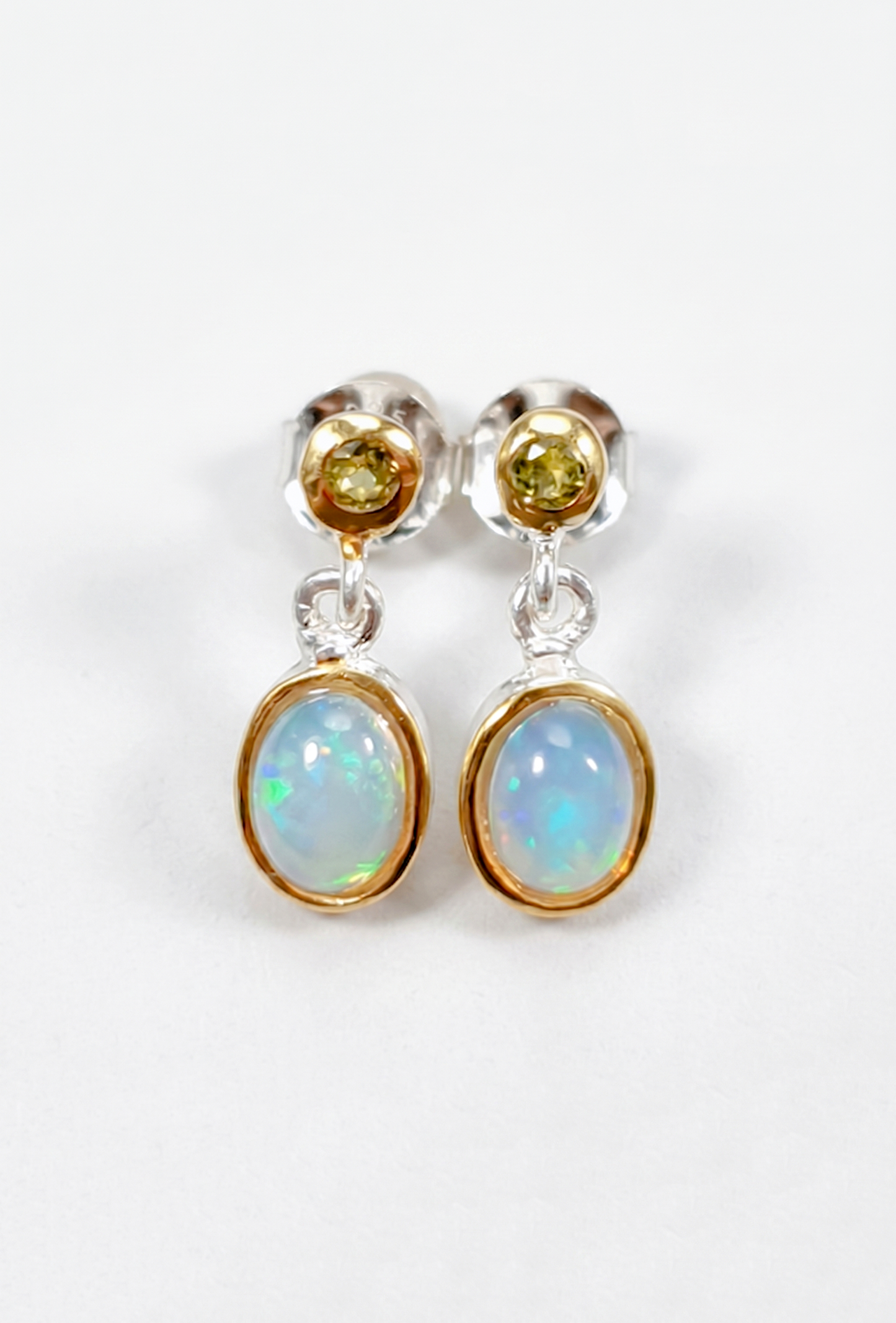 Pair of earrings with opal and yellow gemstones on a white background