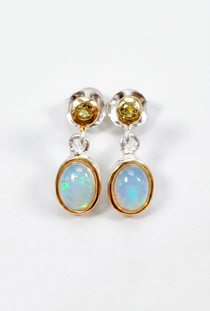 Pair of earrings with opal and yellow gemstones on a white background