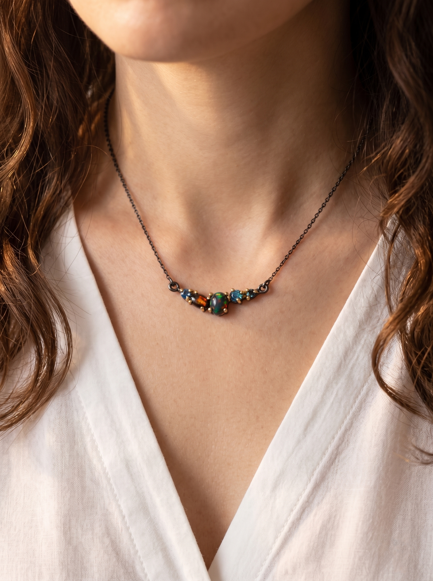Necklace with multicolored black opal worn by a woman in white