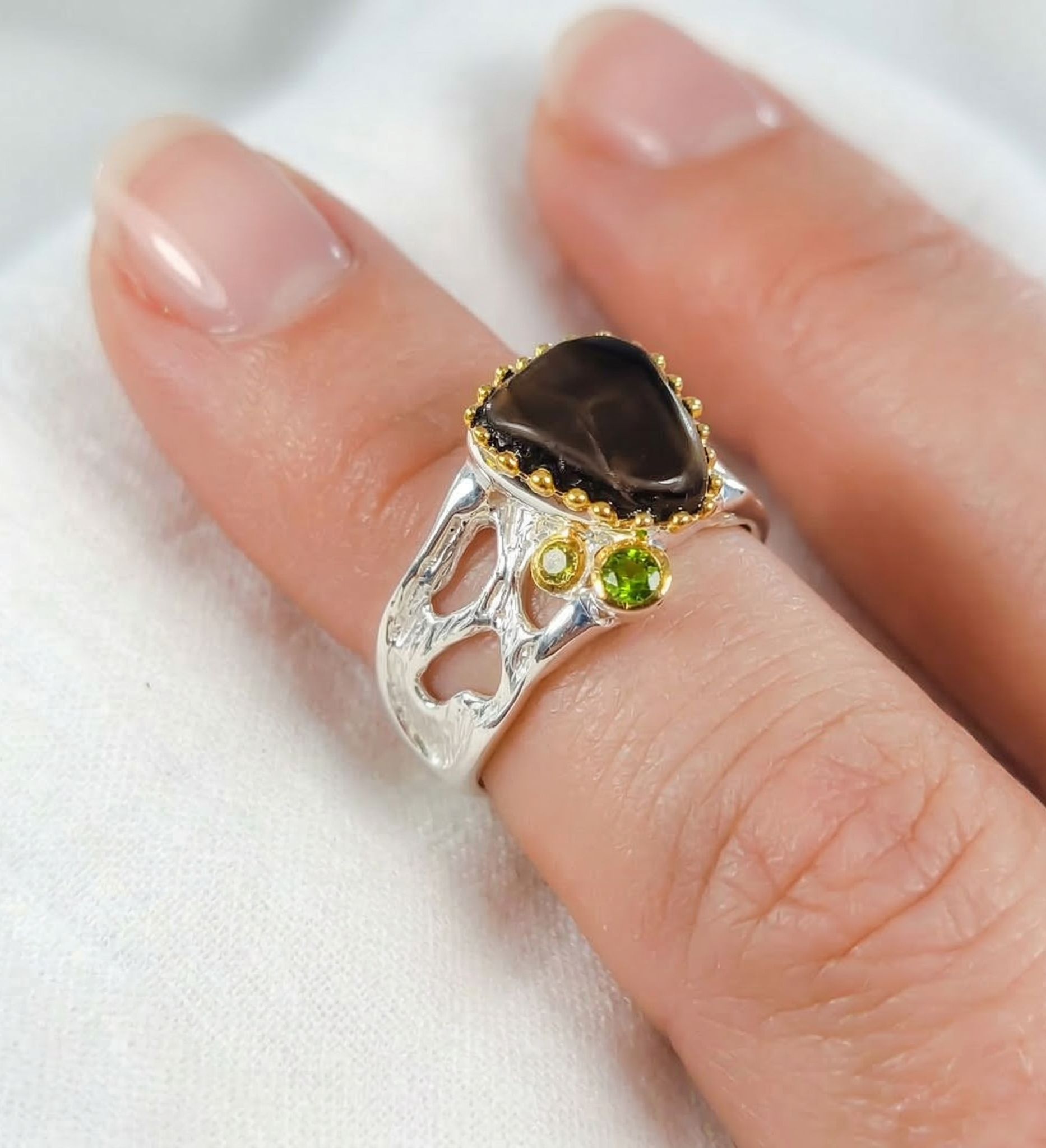Silver ring with gemstones on a finger against a white background